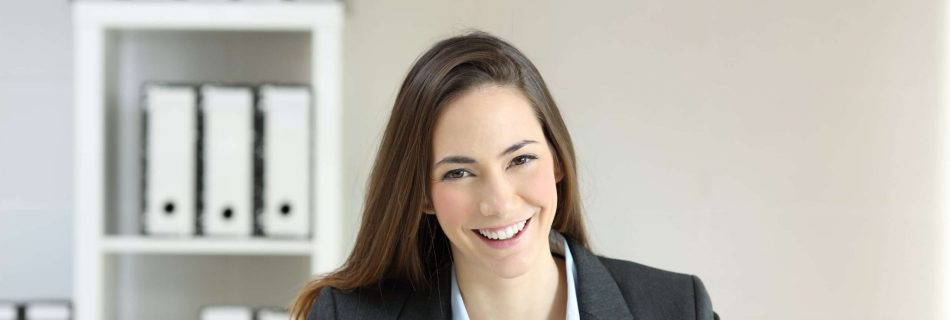 Mitarbeitende im Büro sitz am Schreibtisch und lächelt